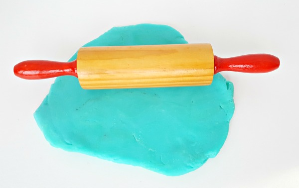 Roll play dough with a rolling pin in a kids sensory activity
